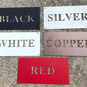May include: Five metal signs with different colors and the words "BLACK", "SILVER", "WHITE", "COPPER", and "RED" cut out of the metal.