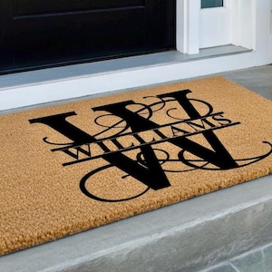 May include: A rectangular doormat with a natural coir fiber appearance. The mat features a large, stylized black letter "W" with the name "WILLIAMS" in a serif font. The design is centered on the mat, suitable for a front door.