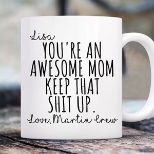 May include: White ceramic mug with a curved handle. The mug features black text that reads "Lisa, YOU'RE AN AWESOME MOM KEEP THAT SHIT UP. Love, Martin crew."
