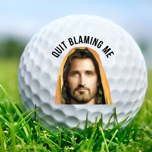 May include: A white golf ball with a picture of Jesus on it. The text "QUIT BLAMING ME" is printed around the image.