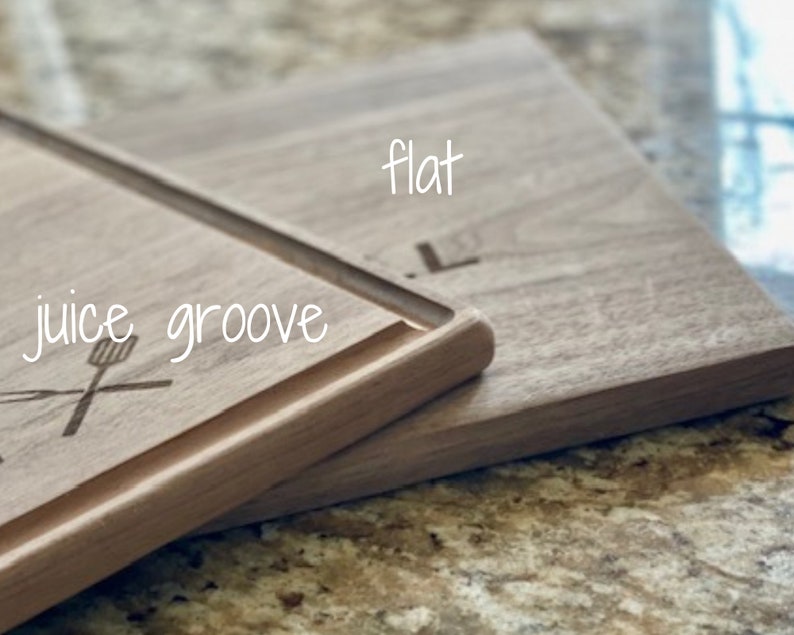 Puede incluir: Tabla de cortar de madera con ranura para jugos y la palabra "flat" grabada en la superficie. Las palabras "juice groove" est&aacute;n escritas en cursiva. Una esp&aacute;tula y un tenedor est&aacute;n grabados en la tabla.