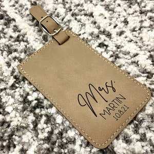 Peut inclure: Une &eacute;tiquette &agrave; bagages en cuir marron avec le texte "Mrs. MARTIN 10.8.21" en noir.