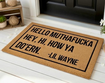 May include: A rectangular doormat with the text "HELLO MUTHA FUCKA HEY, HI, HOW YA DO'ERN." in black, with "-LIL WAYNE" below. The mat is a light brown color and is placed in front of a black door.