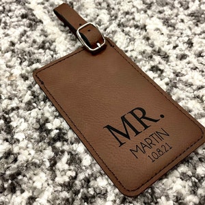 Peut inclure: Etiquette &agrave; bagages en cuir marron avec le texte "MR. MARTIN 10.8.21" grav&eacute; en noir.