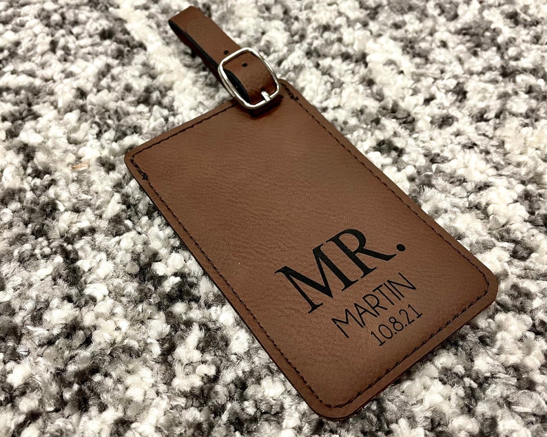 Peut inclure: Etiquette &agrave; bagages en cuir marron avec le texte "MR. MARTIN 10.8.21" grav&eacute; en noir.