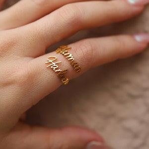 May include: Two gold rings with the names "Hailey" and "Hamzah" engraved on them. The rings are worn on a finger.