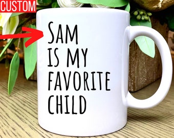 May include: White ceramic mug with a black inscription that reads "SAM IS MY FAVORITE CHILD".