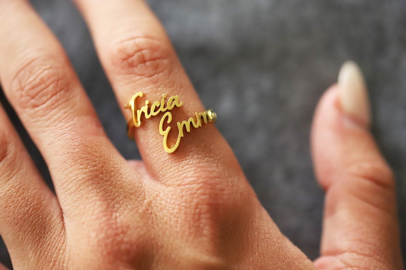 May include: Gold ring with the names "Tricia" and "Emma" written in cursive.