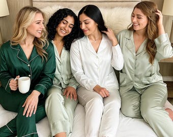 May include: Four matching pajama sets featuring long-sleeved button-down shirts and trousers. One set is dark green, two are sage green, and one is white with the word BRIDE embroidered on the pant leg. Each set has a collar and white piping.
