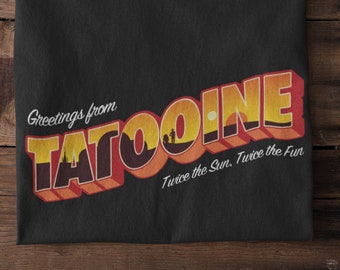 以下が含まれることがあります： 赤い文字と黄色の文字で「Greetings from Tatooine」と書かれた、ビンテージスタイルのポストカードデザインが施された黒いTシャツ。デザインには、2つの太陽が沈む夕焼けのシーンと「Twice the Sun. Twice the Fun.」というテキストも含まれています。