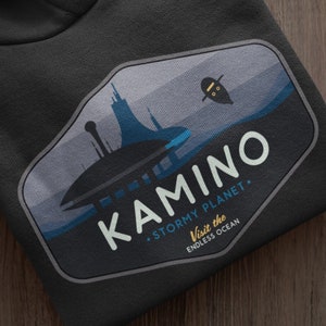 May include: Black hooded sweatshirt with a graphic print of a blue and gray cityscape with the text "KAMINO - STORMY PLANET - Visit the ENDLESS OCEAN".