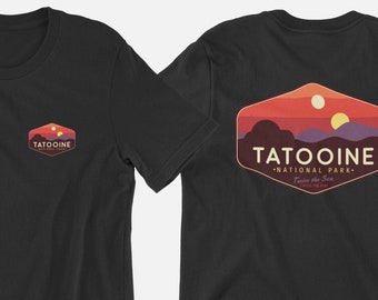Könnte beinhalten: Schwarzes T-Shirt mit einem Vintage-Logo des Tatooine Nationalparks auf der Rückseite. Das Logo zeigt eine Sonnenuntergangsszene mit zwei Sonnen und den Text "Tatooine National Park - Two Suns in the Sky".
