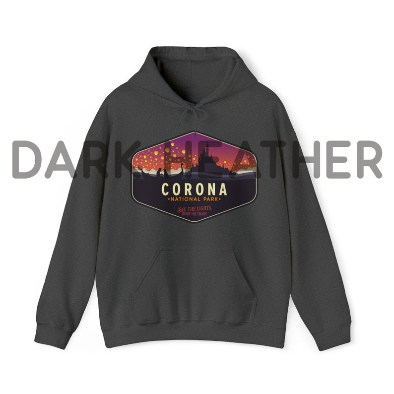 Puede incluir: Sudadera con capucha gris oscuro con bolsillo delantero y cord&oacute;n. La parte delantera presenta un gr&aacute;fico de un castillo y linternas flotantes con el texto "CORONA NATIONAL PARK" y "SEE THE LIGHTS, ENJOY THE SHOW."
