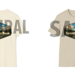 K&ouml;nnte beinhalten: Zwei T-Shirts mit einem Grafikdruck eines Gebirges und dem Text "Gravity Falls National Park" im Vintage-Stil. Die T-Shirts sind in den Farben Natur und Sand erh&auml;ltlich.