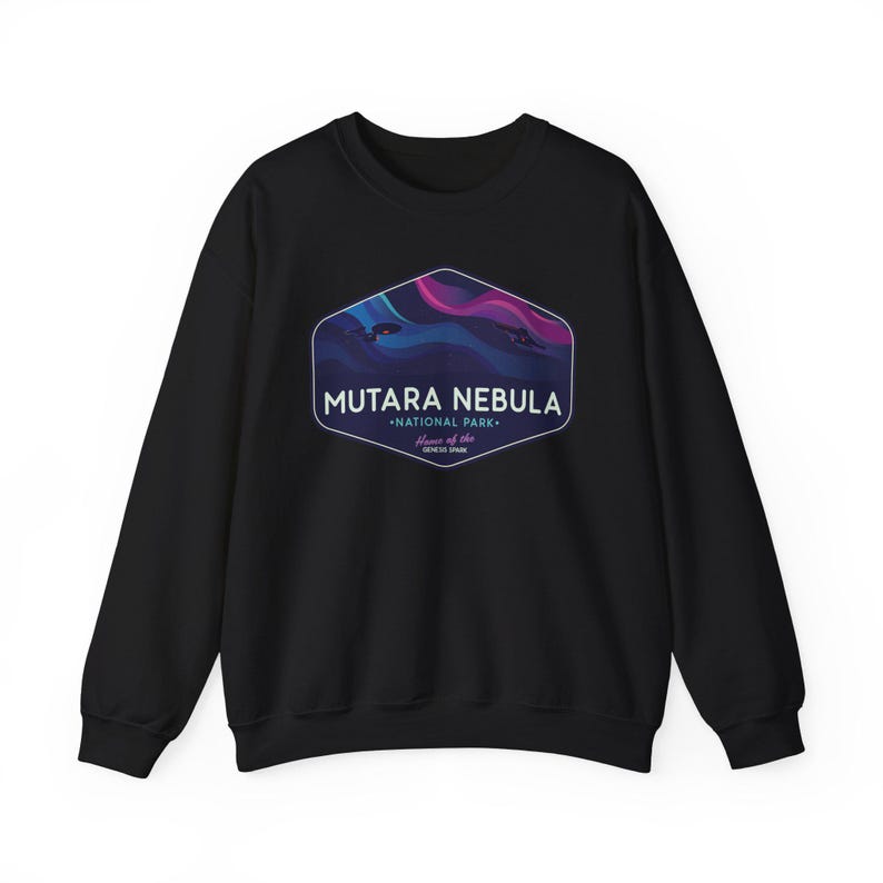 May include: Black crewneck sweatshirt with a graphic featuring the text "MUTARA NEBULA - NATIONAL PARK - Home of the GENESIS SPARK." The graphic has a hexagonal shape with a nebula design in shades of blue, purple, and pink.