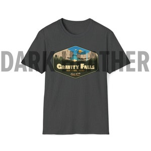 K&ouml;nnte beinhalten: Dunkelgraues T-Shirt mit einem Aufdruck des Gravity Falls National Park Logos. Das Logo zeigt ein stilisiertes Bild eines Wasserfalls, Bergen und B&auml;umen. Der Text "Gravity Falls National Park" ist in einer Vintage-Schriftart geschrieben. Der Text "Home of the Mystery Shack" ist in einer kleineren Schriftart unter dem Haupttext geschrieben.