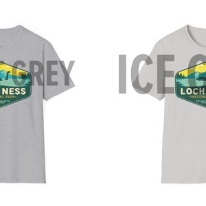 May include: Two t-shirts in different shades of gray, both featuring a vintage-style graphic of Loch Ness National Park with a depiction of the Loch Ness Monster. The text "Loch Ness National Park" is printed on the graphic.
