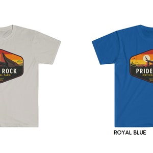 May include: Two t-shirts with a graphic design of a sunset scene with a mountain and the text "Pride Rock National Park" in a vintage style. The t-shirts are available in ice grey and royal blue.