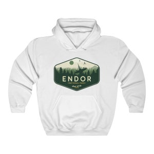 May include: White hooded sweatshirt with a green and white graphic design of a forest scene with a spaceship flying over it. The graphic says "Endor National Park - Home of the Ewoks".