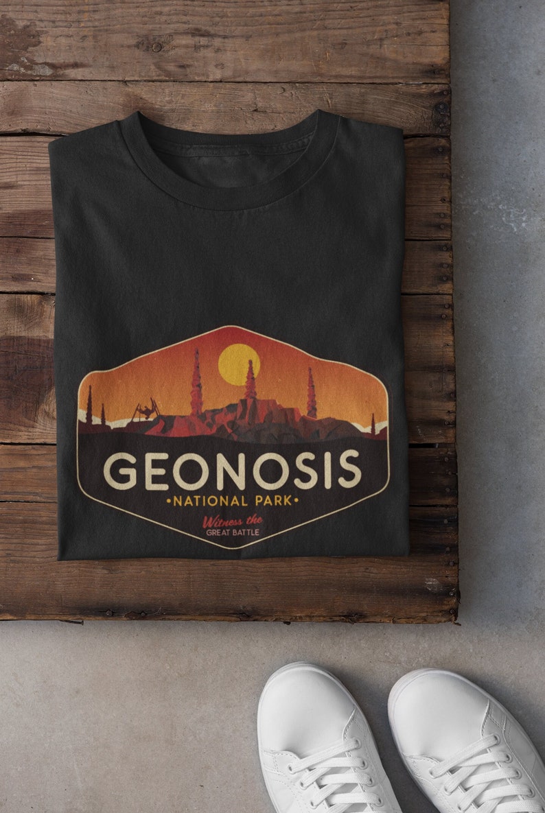 May include: Black t-shirt featuring a vintage-style graphic of a desert landscape with the text "Geonosis National Park. Witness the Great Battle."