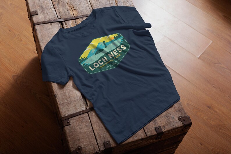 May include: A navy blue t-shirt with a green, yellow, and blue graphic of a Loch Ness Monster in a lake. The graphic says "Loch Ness National Park".