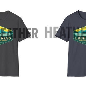 May include: Two t-shirts with a vintage-style graphic of Loch Ness National Park. The shirt on the left is dark heather grey and the shirt on the right is heather navy.