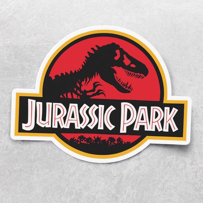 May include: A sticker featuring the Jurassic Park logo. The design includes a black dinosaur skeleton silhouette against a red background, with the words "JURASSIC PARK" in white letters on a black and yellow banner.