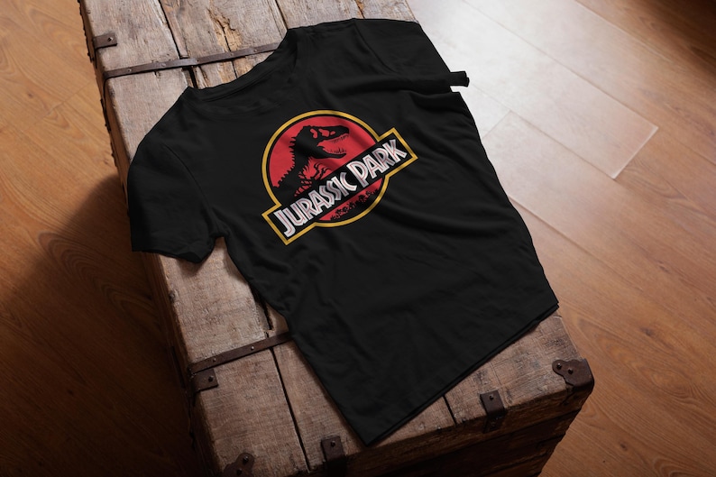 Black unisex T-shirt with the classic Jurassic Park red and yellow dinosaur logo, retro 90s nostalgia graphic tee for men and women.