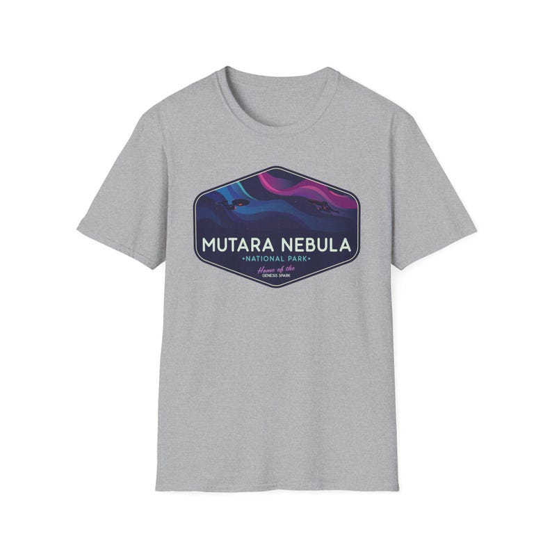 May include: A light gray t-shirt featuring a graphic of the Mutara Nebula National Park. The graphic is a dark blue, purple, and pink design inside a dark blue hexagon shape. The text "MUTARA NEBULA" is above "NATIONAL PARK".