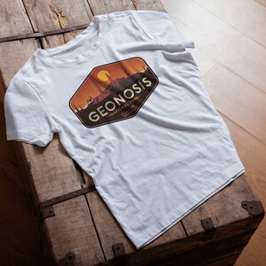 May include: White t-shirt featuring a brown, orange and yellow graphic design of a cityscape with the text "GEONOSIS - NATIONAL PARK" in a vintage style.