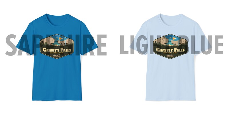 K&ouml;nnte beinhalten: Zwei T-Shirts mit einem grafischen Design eines Retro-Nationalpark-Logos. Das Logo zeigt eine Bergkette, einen See und den Text "Gravity Falls National Park". Das T-Shirt links ist saphiblau, das T-Shirt rechts ist hellblau.