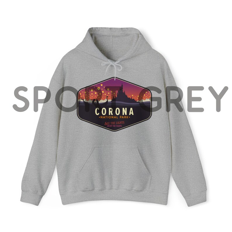 Puede incluir: Una sudadera con capucha gris claro con un bolsillo delantero y una capucha con cord&oacute;n. La sudadera presenta un gr&aacute;fico de un castillo y linternas flotantes con el texto "CORONA NATIONAL PARK" y "SEE THE LIGHTS, ENJOY THE SHOW".