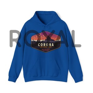 Puede incluir: Sudadera con capucha azul real con bolsillo delantero y capucha con cord&oacute;n. La parte delantera presenta un gr&aacute;fico de una escena nocturna con el texto "CORONA NATIONAL PARK" y "SEE THE LIGHTS ENJOY THE STARS".