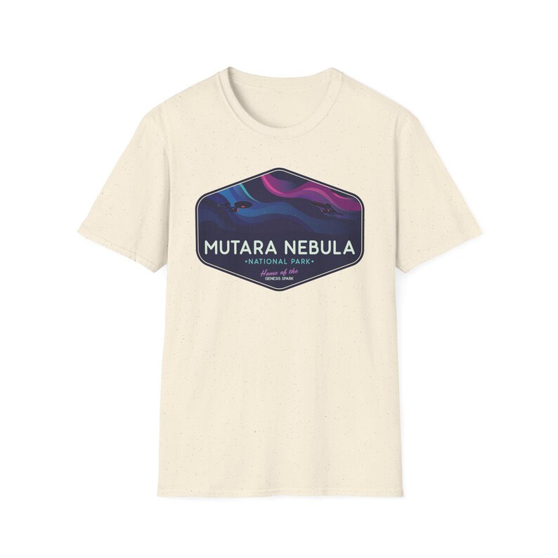 May include: Cream-colored t-shirt featuring a graphic of the Mutara Nebula National Park. The design includes a dark blue and purple nebula illustration within a dark blue hexagon shape. The text "MUTARA NEBULA" and "NATIONAL PARK" are also displayed.