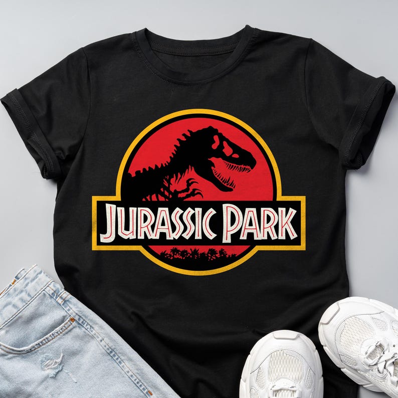 Black unisex T-shirt with the classic Jurassic Park red and yellow dinosaur logo, retro 90s nostalgia graphic tee for men and women.