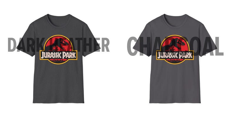 May include: Two dark gray t-shirts with the Jurassic Park logo. The logo features a red circle with a dinosaur silhouette, a yellow border, and the words "JURASSIC PARK" in white. The shirts are displayed on a white background.