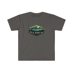 K&ouml;nnte beinhalten: Ein dunkelgraues T-Shirt mit einer gr&uuml;nen und gelben Grafik einer Bergkette mit einer Dinosauriersilhouette und einem gelben Mond. Die Grafik ist in einer sechseckigen Form mit dem Text "Visit Isla Nublar - National Park" darunter.
