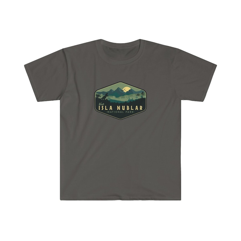 K&ouml;nnte beinhalten: Ein dunkelgraues T-Shirt mit einer gr&uuml;nen und gelben Grafik einer Bergkette mit einer Dinosauriersilhouette und einem gelben Mond. Die Grafik ist in einer sechseckigen Form mit dem Text "Visit Isla Nublar - National Park" darunter.