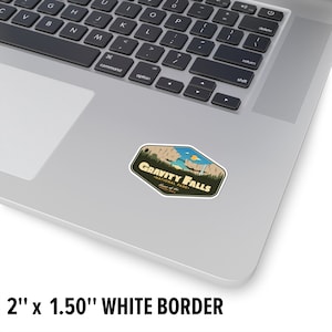 May include: A sticker featuring a retro-style illustration of a mountain range with a waterfall, with the text "Gravity Falls National Park" in a brown banner. The sticker is 2 inches by 1.5 inches and has a white border.