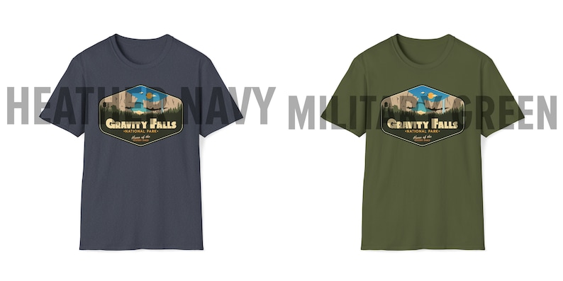K&ouml;nnte beinhalten: Zwei T-Shirts mit einem Grafikdruck eines Retro-Nationalpark-Logos. Das Logo zeigt eine Bergkette, einen See und den Text "Gravity Falls National Park". Die T-Shirts sind in den Farben Heather Navy und Milit&auml;rgr&uuml;n erh&auml;ltlich.
