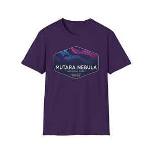 May include: A purple t-shirt featuring a graphic of the Mutara Nebula National Park. The graphic is a stylized depiction of a nebula with blue, pink, and purple hues, and the text "MUTARA NEBULA - NATIONAL PARK - Home of the Genesis Span."