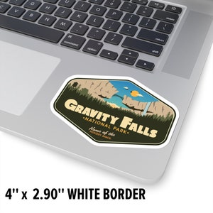 May include: A sticker featuring a retro-style illustration of a mountain range with a waterfall and a bridge. The text reads "Gravity Falls - National Park - Home of the Mystery Shack". The sticker is 4 inches by 2.90 inches and has a white border.