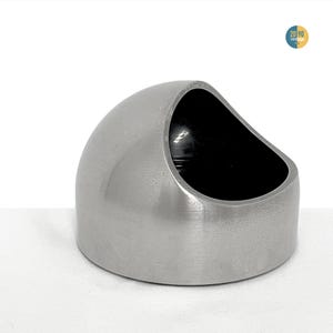 May include: A brushed stainless steel bowl with a dome-shaped exterior and a slanted, open top. The interior of the bowl is finished in a deep, solid black color. The object features a smooth, metallic surface with a circular base and a wide opening.