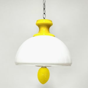 May include: A white and yellow glass pendant light with a rounded dome shape and a small yellow bulb hanging from the bottom.
