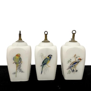 May include: Three white porcelain bottles with brass tops, each decorated with a different colourful bird illustration. The birds are perched on branches, displaying a variety of vibrant colours. The bottles have a classic, elegant design.