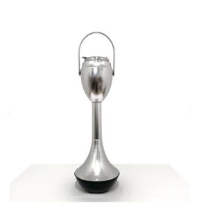 Può includere: Un posacenere da terra alto, realizzato in metallo color argento lucido. Il design presenta una parte superiore arrotondata a forma di ciotola con un manico incernierato, sostenuta da uno stelo cilindrico sottile che si allarga in un'ampia base nera zavorrata.