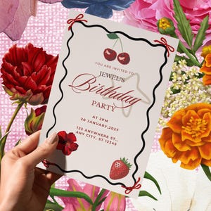 Op de afbeelding: Een verjaardagsuitnodiging met een bloemenontwerp. De uitnodiging heeft een zwarte rand met rode strikken en bevat kersen, een aardbei en de tekst "Jewel's Birthday Party". De achtergrond bevat verschillende bloemen.