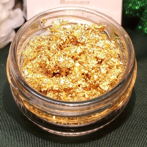May include: A glass jar filled with gold glitter. The jar is clear and has a wide mouth. The glitter is a fine, sparkly gold.