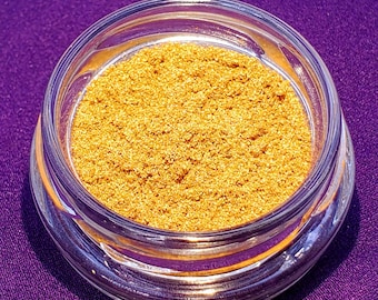 May include: A small glass jar filled with a golden glitter powder.