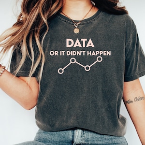 May include: A dark gray t-shirt with the text "DATA OR IT DIDN'T HAPPEN" and a line graph with pink circles.